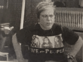 woman stands with hands on hips wearing a "we the people" shirt.